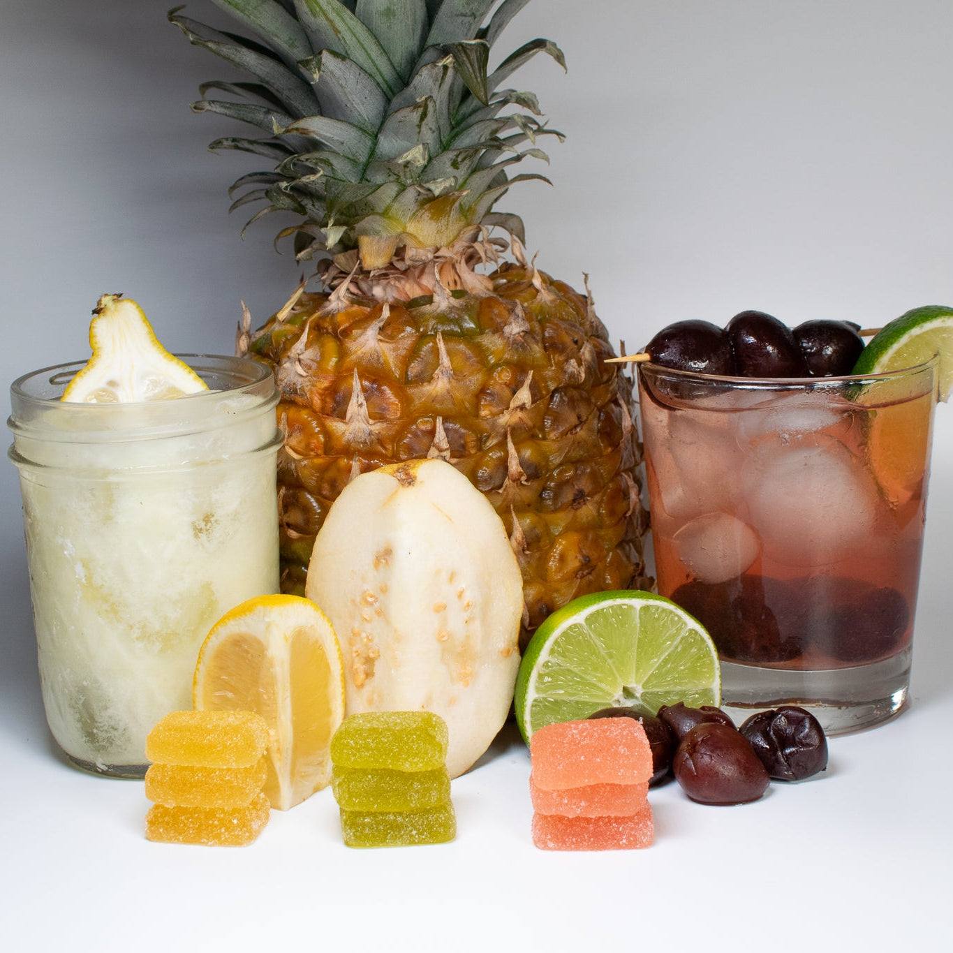 Colorful assortment of Signature Gummies Bundle with fresh fruits and drinks, showcasing vibrant flavors and refreshing appeal.