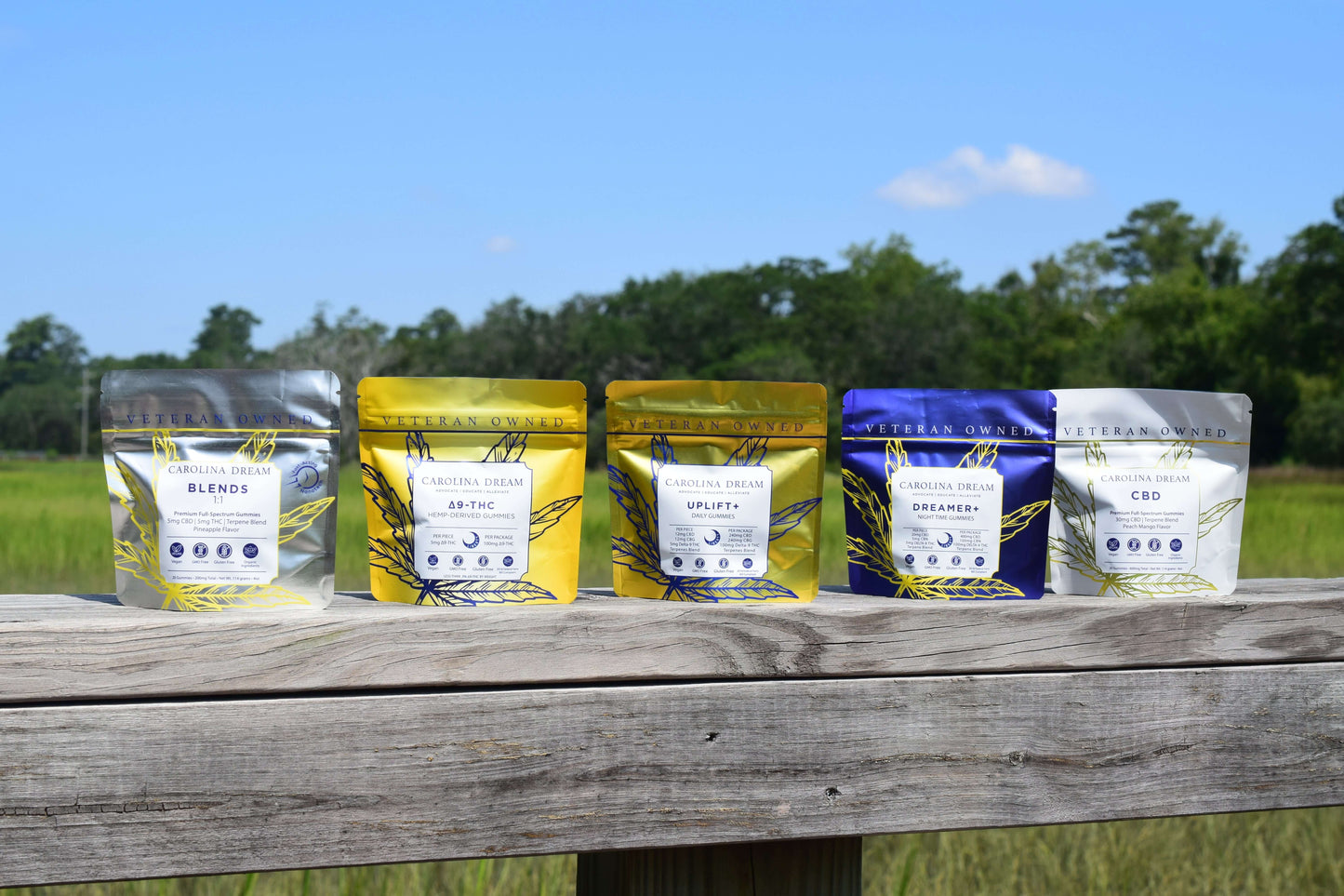 The Dream Team Bundle featuring five cannabis gummy packs arranged on a wooden railing with a scenic background.